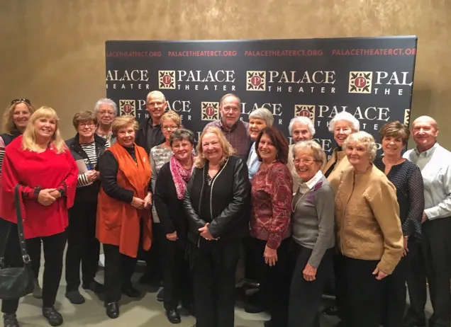 group of older people in front of palace theater signs