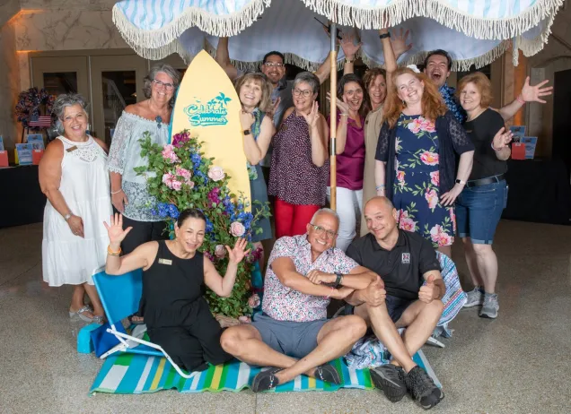 group of people posing under a beach umbrella